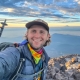 young man smiling on summit of mount st helens in washington on a teen adventure camp