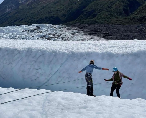 Two young girls ice climbing on the Matanuska Glacier in Alaska on a teen summer outdoor adventure camp
