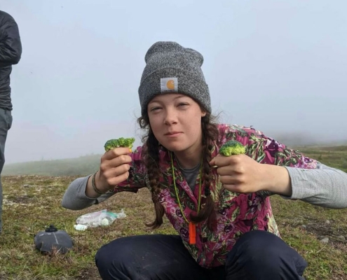Teenage girl cooking broccoli in the backcountry of Alaska
