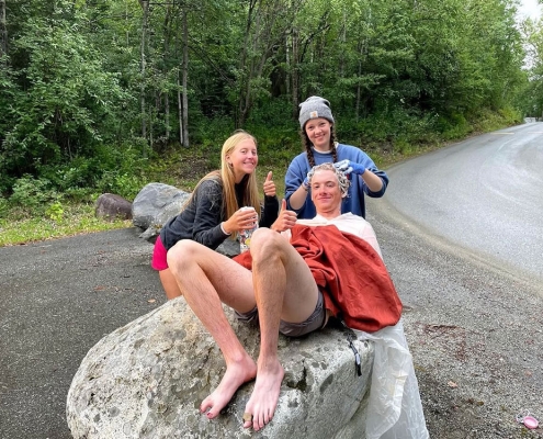 Teenage boy and girls washing their hair in the backcountry of Alaska on a summer teen adventure camp