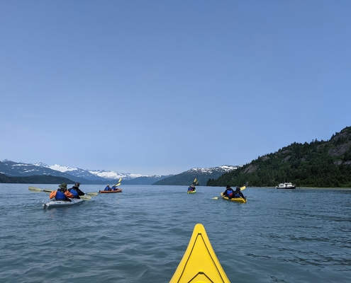 Group of teens sea kayaking in Prince William Sound in Alaska during a summer outdoor adventure camp