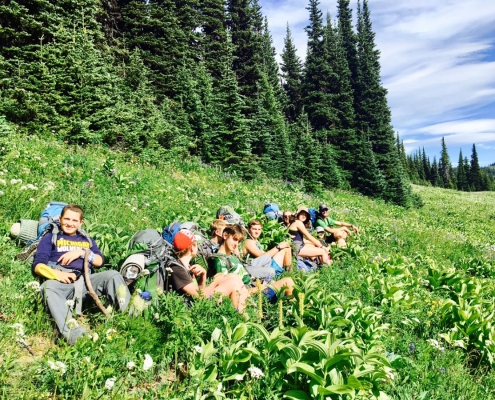 students taking a break trekking in lush green fields in british columbia