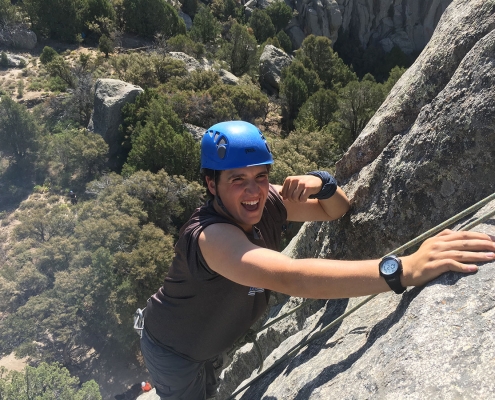 young boy rock climbing on boulder in idaho at outdoor adventure camp