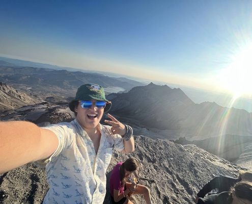 teen boy taking a celebratory selfie on top of mount st helens during summer adventure camp