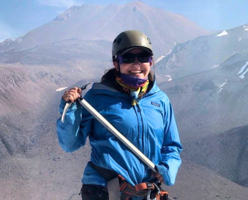 young woman posing with ice axe at summit at summer adventure camp young woman posing with ice axe at summit at summer adventure camp