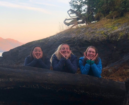 teen girls smiling while leaning on a tree trunk at adventure camp teen girls smiling while leaning on a tree trunk at adventure camp