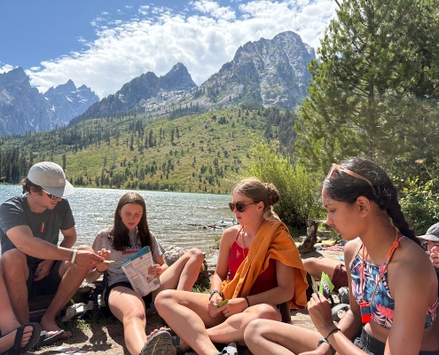yellowstone-tetons-teens-sitting-at-alpine-lake-playing-a-game yellowstone-tetons-teens-sitting-at-alpine-lake-playing-a-game
