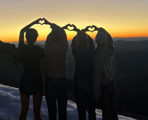 Teen girls standing with their hands creating a heart shape on Mt. Lassen in California