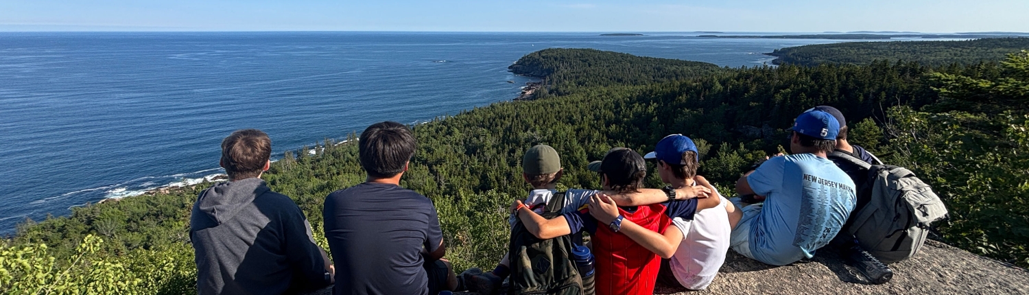 NED3-26-IMG_2043-(9)-banner Teen boys and girls sitting on a rock outcropping in Maine's Acadia National Park with their arms around each other