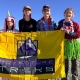 Teenagers standing atop the summit of Mount St. Helens with a yellow Adventure Treks flag