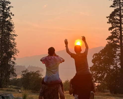 Teen boys sitting on each other's shoulders enjoying a sunset view in Washington